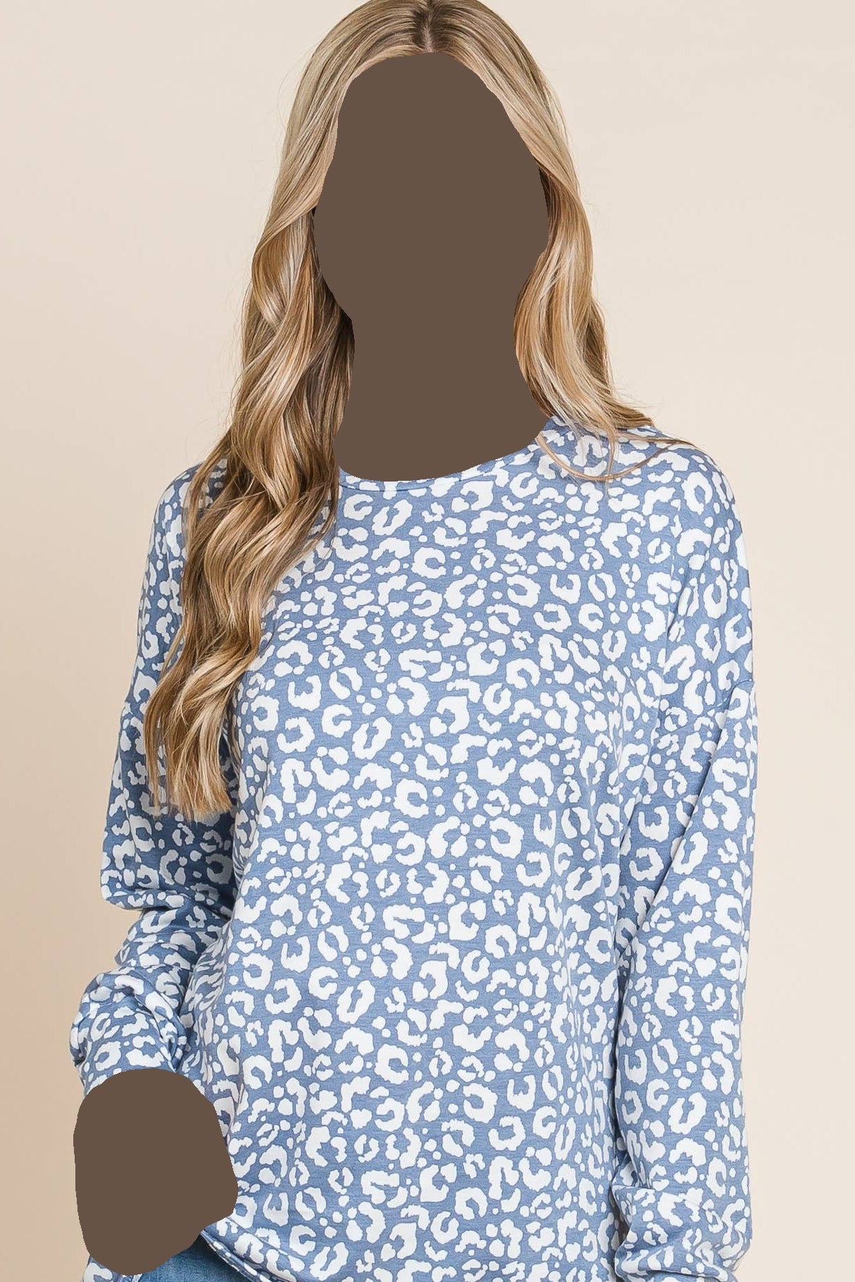 Woman wearing a blue leopard print top and jeans on a beige background